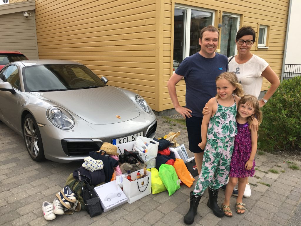Familj med packning framför en Porsche 911